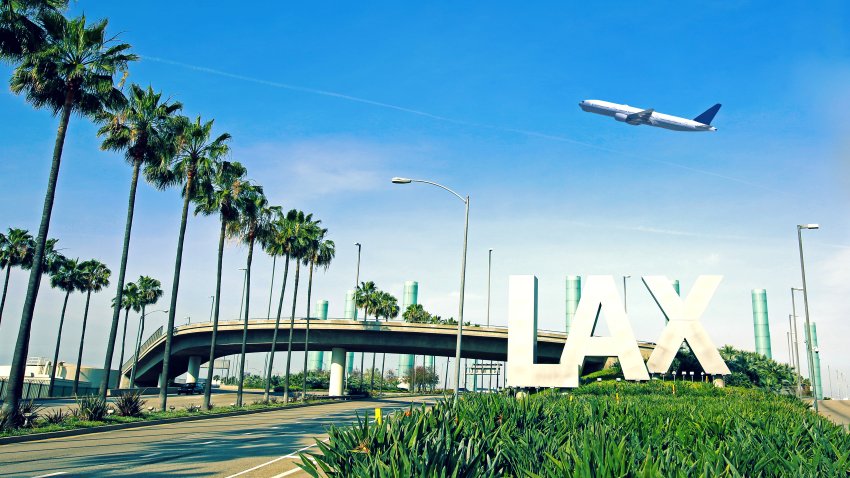 Los Angeles Airport sign with airplane flying overhead.