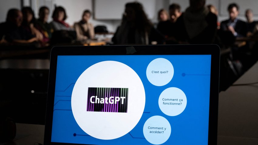 Teachers are seen behind a laptop during a workshop on ChatGPT