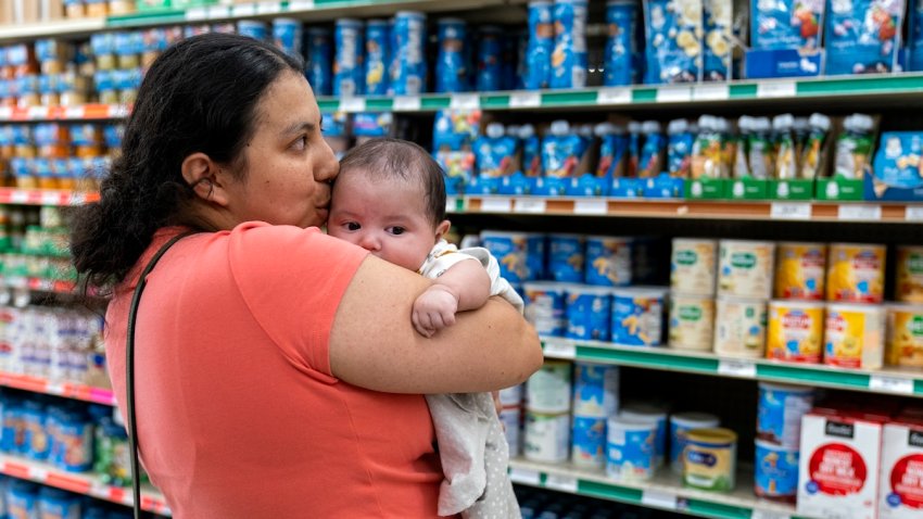 FILE – Yury Navas, 29, of Laurel, Md., kisses her two-month-old baby Jose Ismael Gálvez, at Superbest International Market in Laurel, Md., May 23, 2022, while looking for formula.