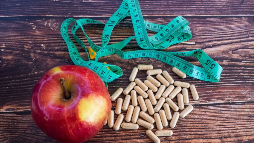 A red apple next to a tape measure and a pile of fiber pills