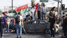 Compton, CA June 7, 2025 Protesters on top of burnt cars in Compton, Calif., Saturday, June 7, 2025, after federal immigration authorities conducted operations. (Gina Ferazzi/Los Angeles Times via Getty Images)