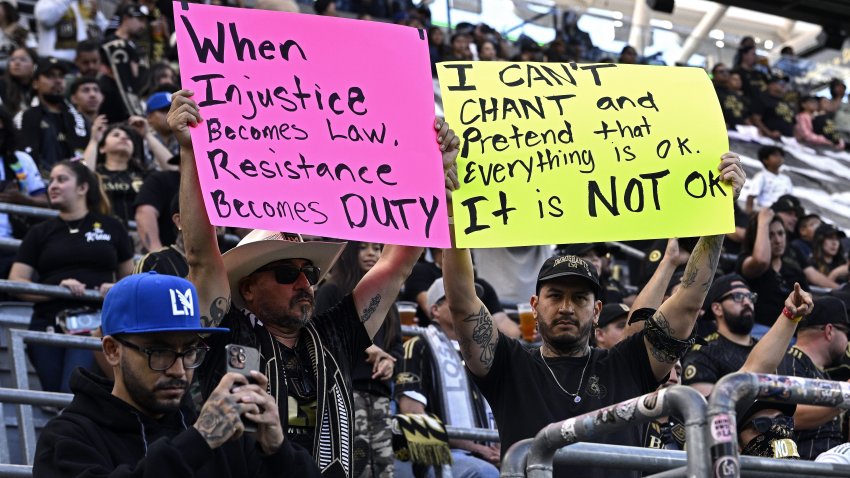 Fans hold up protest signs in the stands before the game between Sporting Kansas City and Los Angeles FC at BMO Stadium on June 08, 2025 in Los Angeles, California.