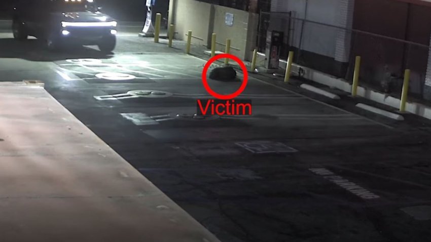 A victim lies on the ground of a parking lot.