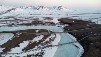 An aerial view of the Dalton Highway and a portion of the Trans Alaska Pipeline System (TAPS) crossing over the frozen Atigun River during the early morning hours of May 9, 2025 about 22 miles north of Atigun Pass in North Slope Borough, Alaska.