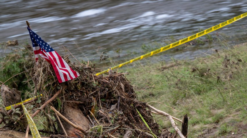 An American flag is stationed over caution tape on the banks of the Guadalupe River in Kerrville, Texas.