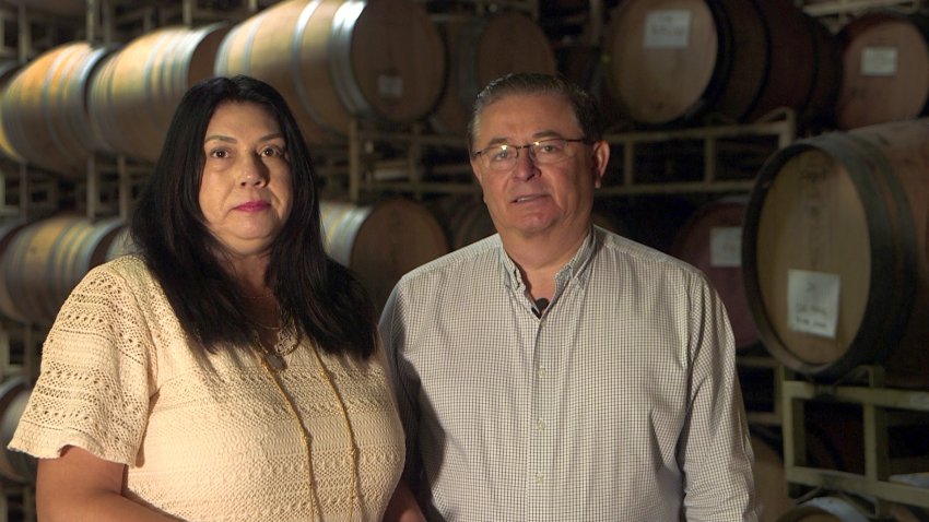 Carlos and Linda Chavez stand in front of barrels bearing the name Chavez Family Cellars in Healdsburg.