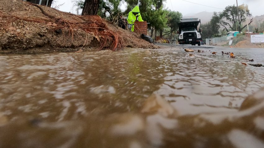 Altadena, CA – October 14: Rain and mud flow down Canon Blvd. amid intermittent downpours as Oscar Turcios puts up fencing around a property that was destroyed in the Eaton fire in Altadena Tuesday, October. 14, 2025. A brief but substantial storm brings heavy rain, thunderstorms and flooding to Southern California today, prompting evacuation warnings for residents near recent burn areas. The storm is expected to produce between three-quarters of an inch to an inch-and-a-half of precipitation across most areas, with 2 to 4 inches possible on south-facing mountain slopes. (Allen J. Schaben / Los Angeles Times via Getty Images)