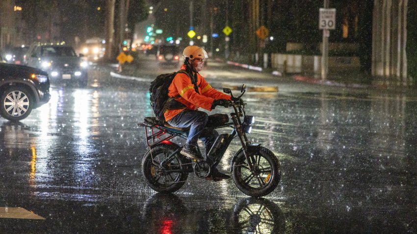 Long Beach, CA – November 14: A bicyclist wears rain gear while crossing Ocean Blvd., in the rain in Long Beach Friday, Nov. 14, 2025. Residents and businesses are bracing for stormy weather expected to soak much of the region Friday and into the weekend.  (Allen J. Schaben / Los Angeles Times via Getty Images)
