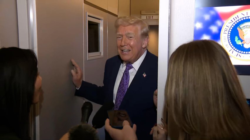 Trump smiles at reporters on Air Force One