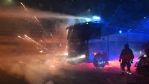 Fireworks explode next to a police truck spraying water to demonstrators