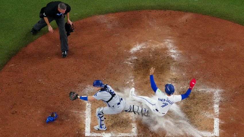 Will Smith #16 of the Los Angeles Dodgers tags out Isiah Kiner-Falefa #7 of the Toronto Blue Jays at home in the ninth inning during Game Seven of the 2025 World Series.
