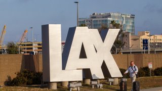 A passenger rolls his luggage on Sepulveda Blvd near Los Angeles International Airport (LAX) Los Angeles, California, on May 15, 2026. (Photo by Apu GOMES / AFP via Getty Images)