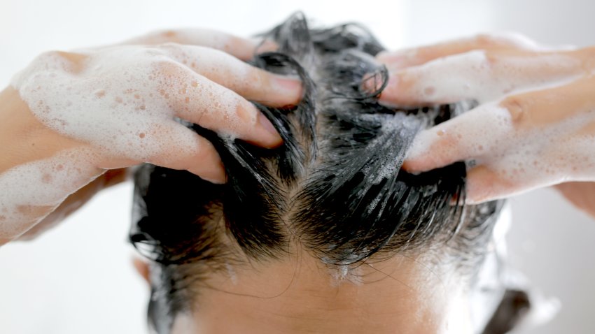 Woman is washing her hair with shampoo