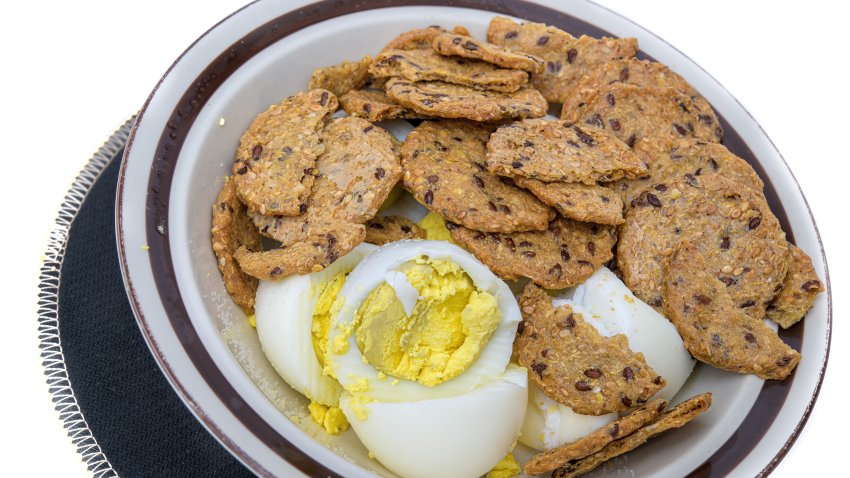 Bowl with sliced hard boiled eggs and multigrain crackers.