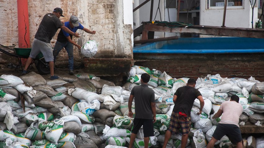 Residents place sandbags as a protective barrier against strong waves generated by Hurricane Polo at Playa Azul.