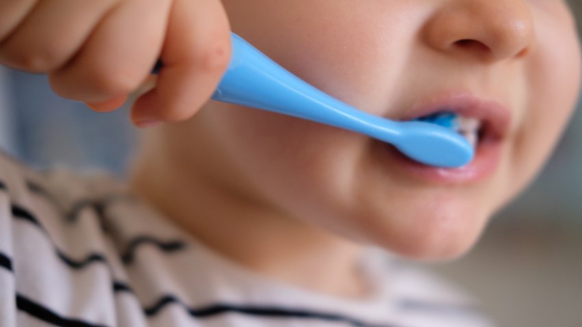 Baby brushing teeth with blue toothbrush
