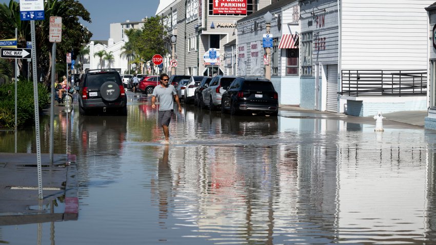 NEWPORT BEACH, CA – October 09: A man crosses E. Bay Ave on the Balboa Peninsula after high tides flooded streets in Newport Beach on Friday, October 9, 2026. A hurricane swell and an overlapping south swell, combined with high tide brought flooding along the California coast. (Photo by Paul Bersebach/MediaNews Group/Orange County Register via Getty Images)
