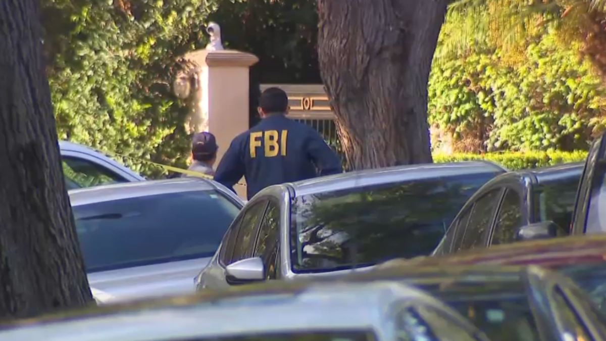 FBI tape and law enforcement vehicles outside the Beverly Hills mansion