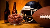 Football sports helmet and football on table with pretzels and beer. Superbowl party!