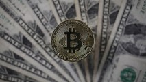 This Dec. 7, 2017, file photo shows a visual representation of the digital cryptocurrency bitcoin alongside U.S. dollars in London.